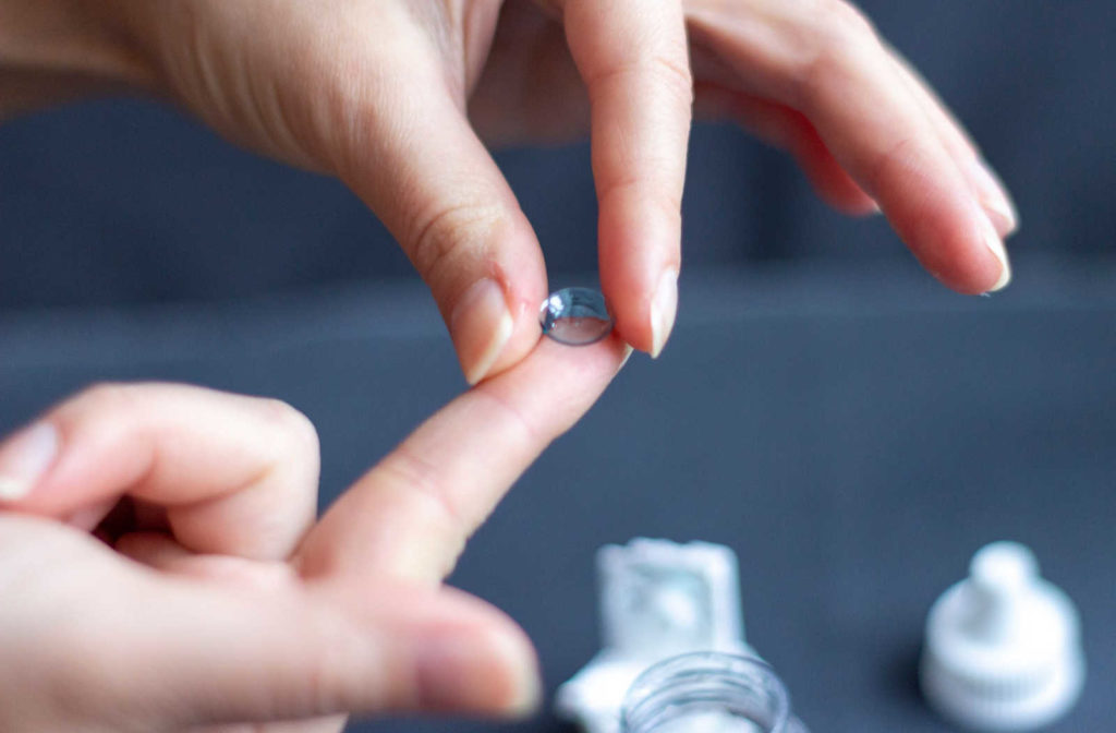 A person placing a contact lenses on there finger tip that can help treat keratoconus