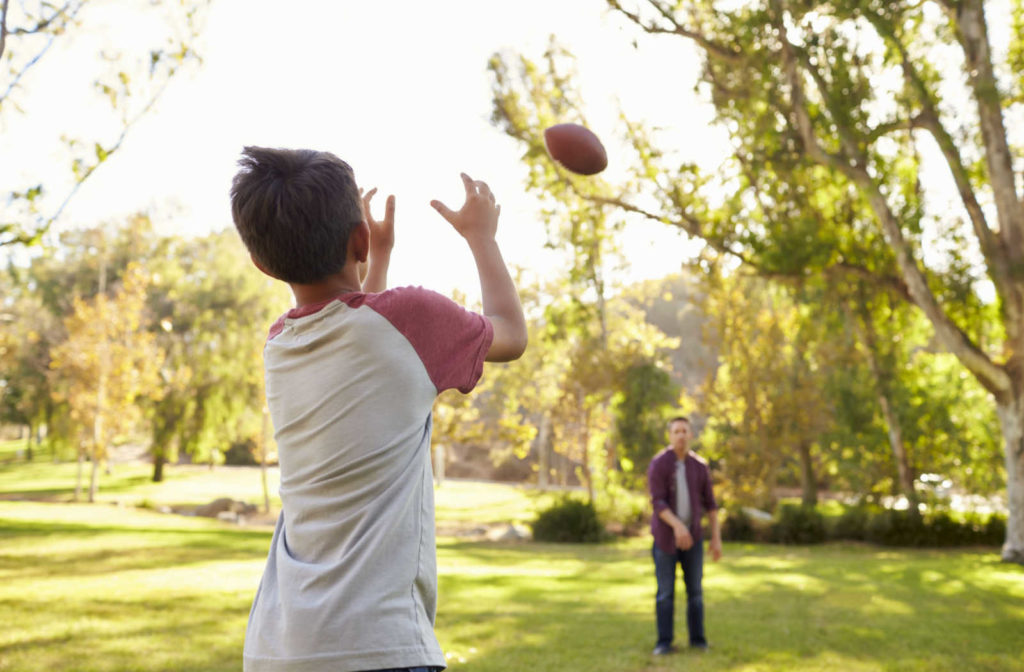 A young boy and his father throwing a football back and forth to demonstrate his hand-eye coordination and visual tracking skills