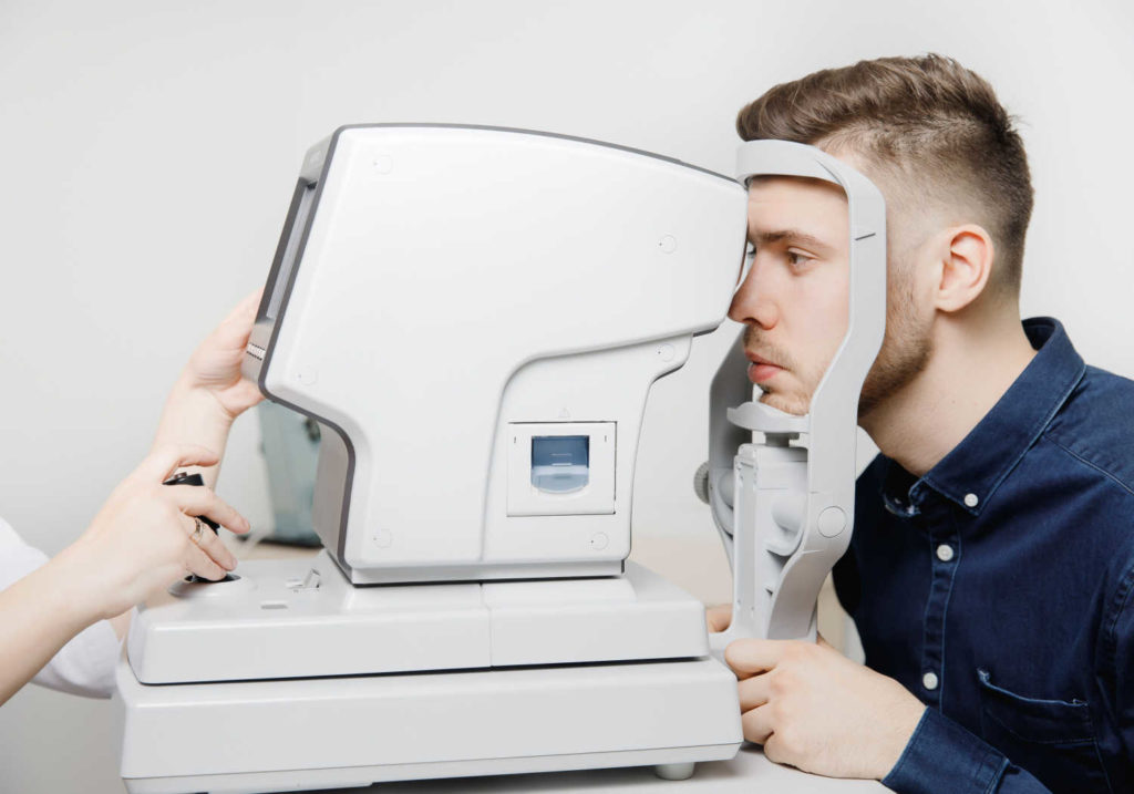 A patient at the eye doctor during a regular eye exam getting his eyes tested for signs of glaucoma during an OCT scan