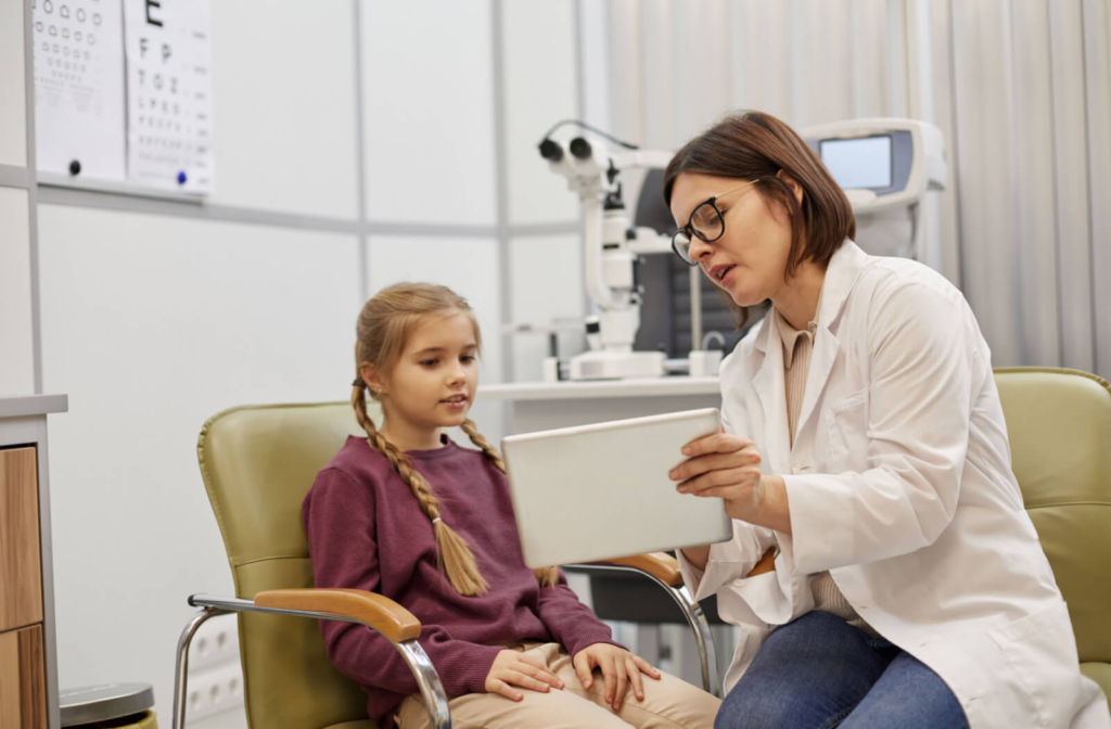 An optometrist explaining her diagnosis to a young girl using a tablet.
