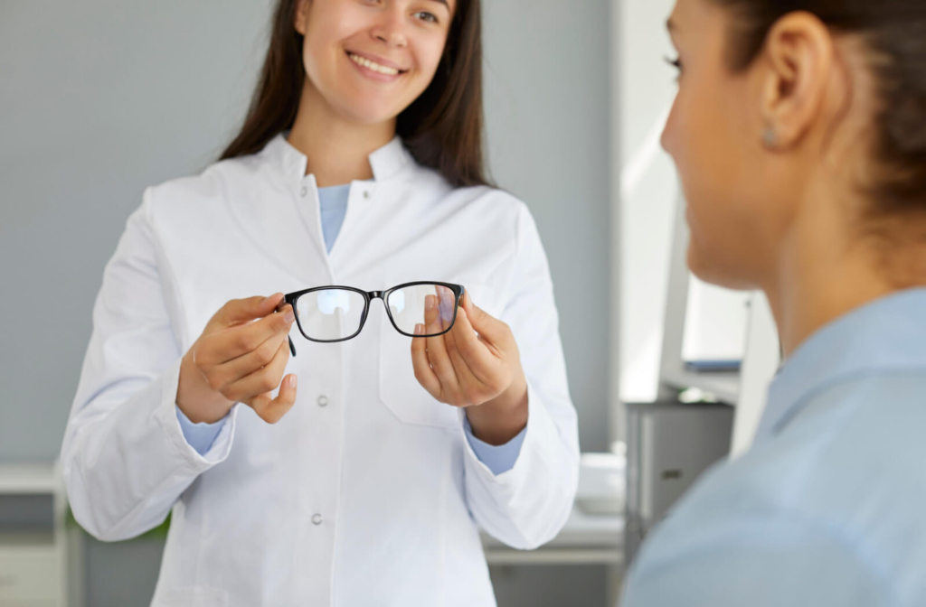 An optometrist happily presenting a pair of glasses to her patient.